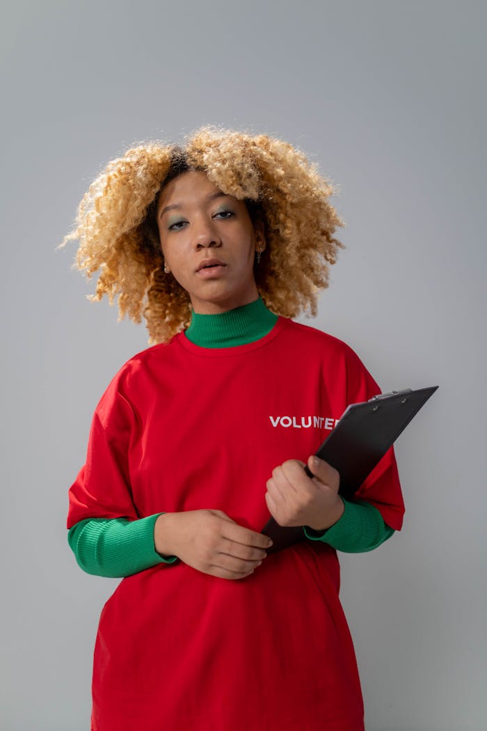 The Art of Drawing Readers In: Your attractive post title goes here Young volunteer woman with curly hair holding a clipboard in a studio setting.